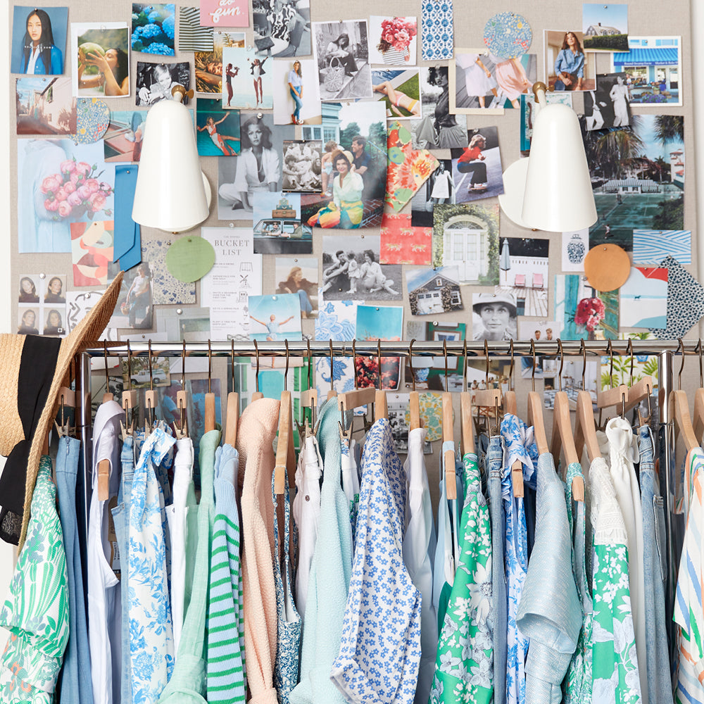 Mood board with swatches and snapshots behind a clothing rack featuring classic, effortless dresses, blouses, and outerwear in soft pastels, with fun, wide-brimmed straw hats.