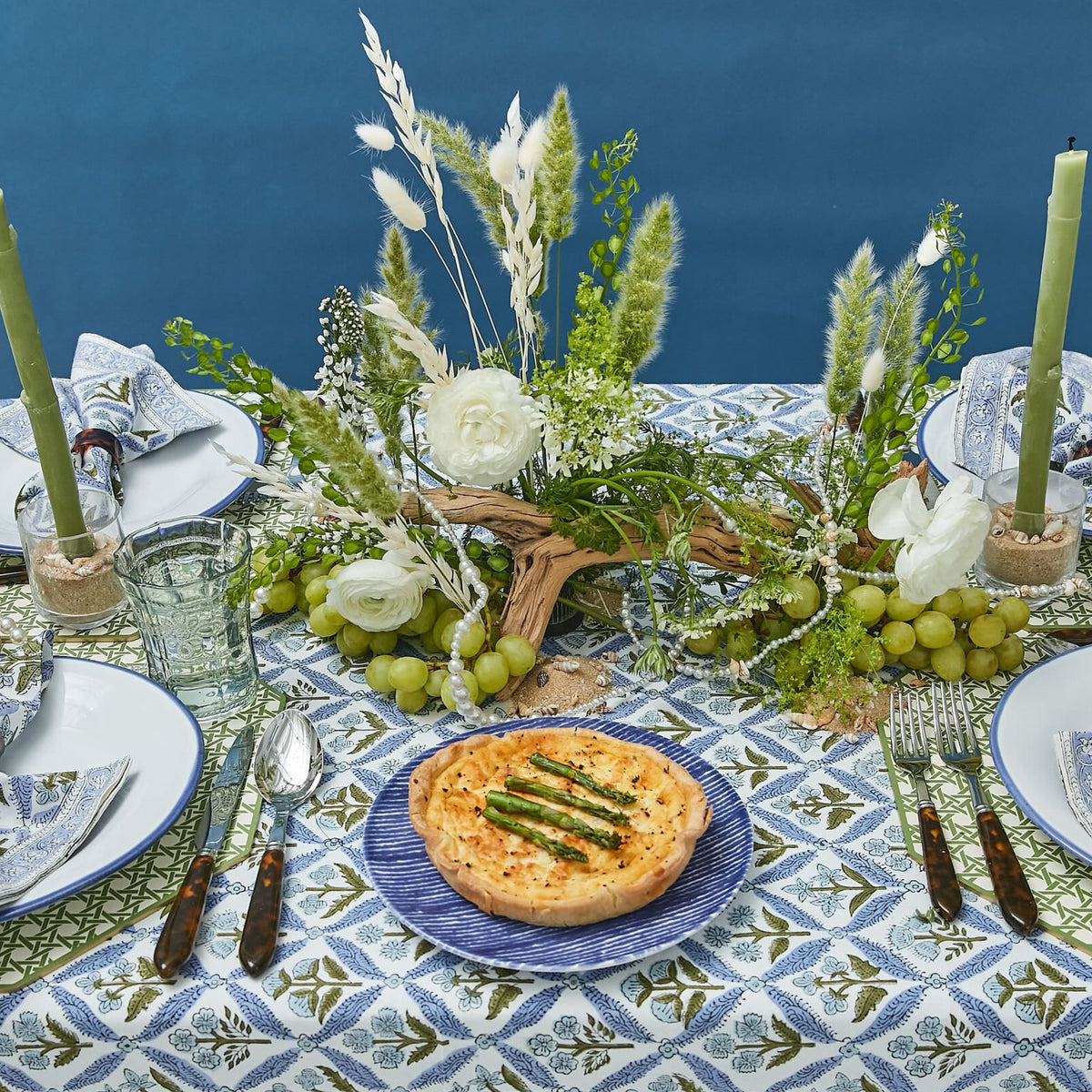 Classic dining table set with an asparagus quiche on a blue-striped plate, elegant centerpiece, and coordinated dishware, creating an effortless, high-end, fun spring tablescape.