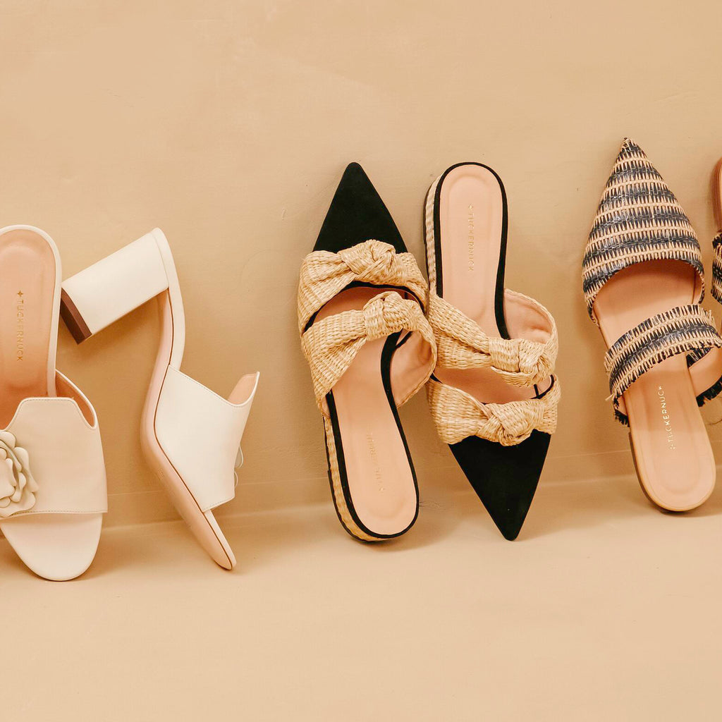 Flat-lay of classic, high-end women's slip-on shoes, featuring effortless mules and sandals with fun, elegant designs in neutral tones for a summery vibe.