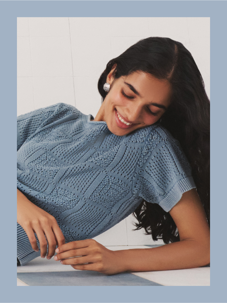 Woman in a blue crochet short sleeved top.