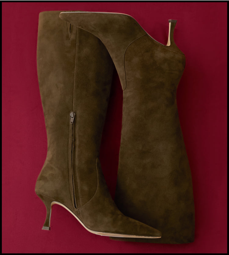 Tall brown suede boots on a red background.