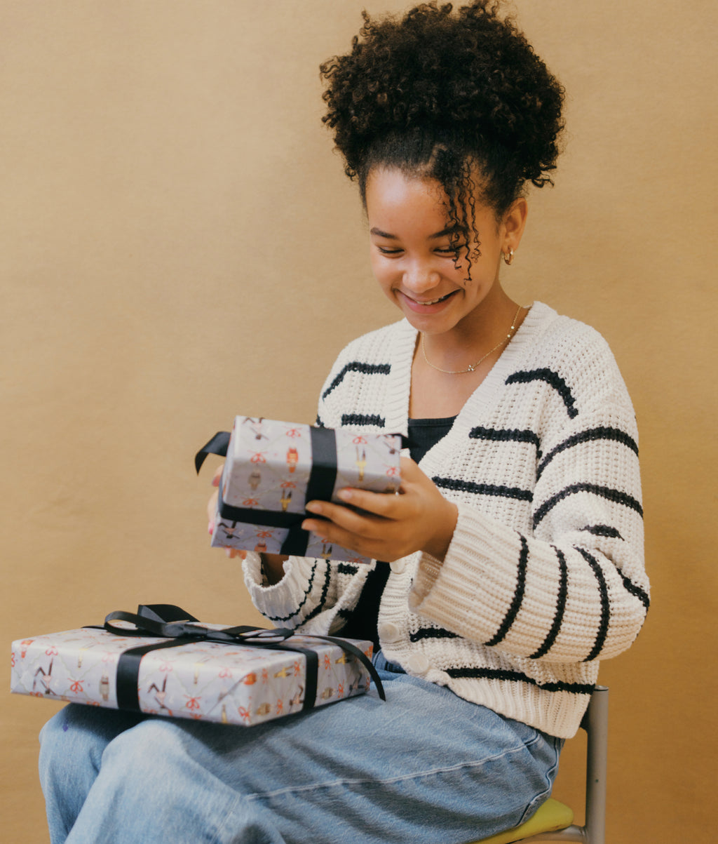 Girl holding presents wrapped in our Children's National wrapping paper.