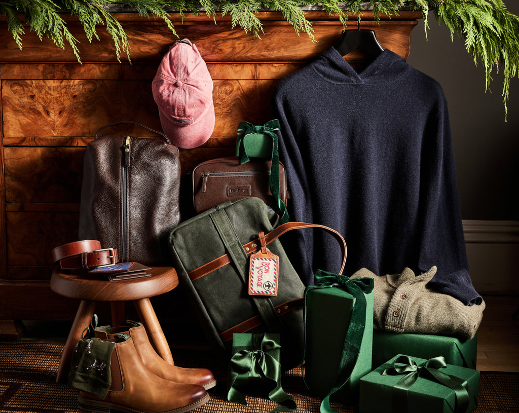 A selection of mens' gifts including a hoodie, leather goods, boots, and a hat.