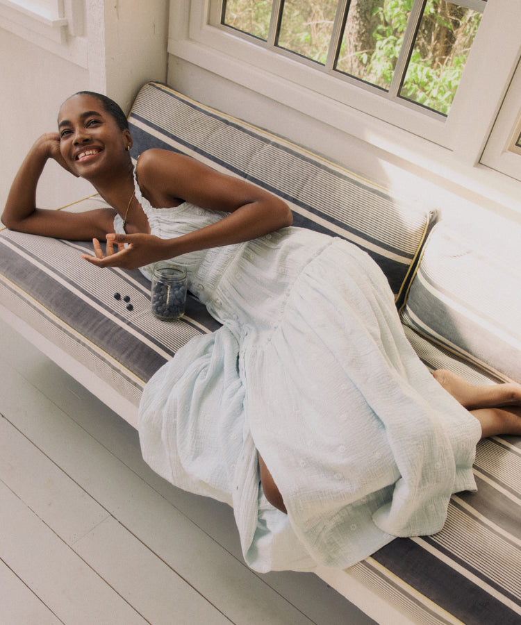 Woman lying on her side on a couch in a blue gauze dress.