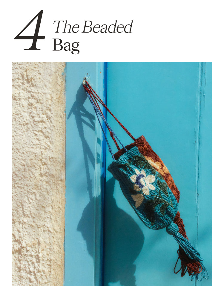4 The Beaded Bag Two floral beaded mini bags, one blue and one brown, blowing in the wind from a post on a blue door.