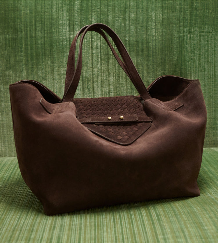 Brown suede bag on a green background.