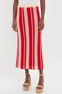 A woman wears a beige and red crochet midi skirt with vertical striped design, styled with tan platform sandals.