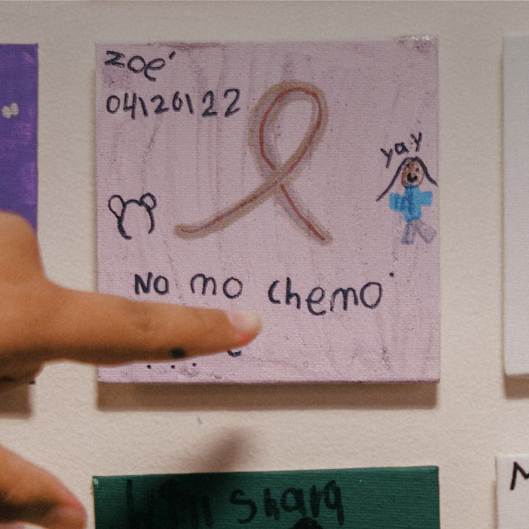 Girl pointing to the tile she painted on her last day of chemo.