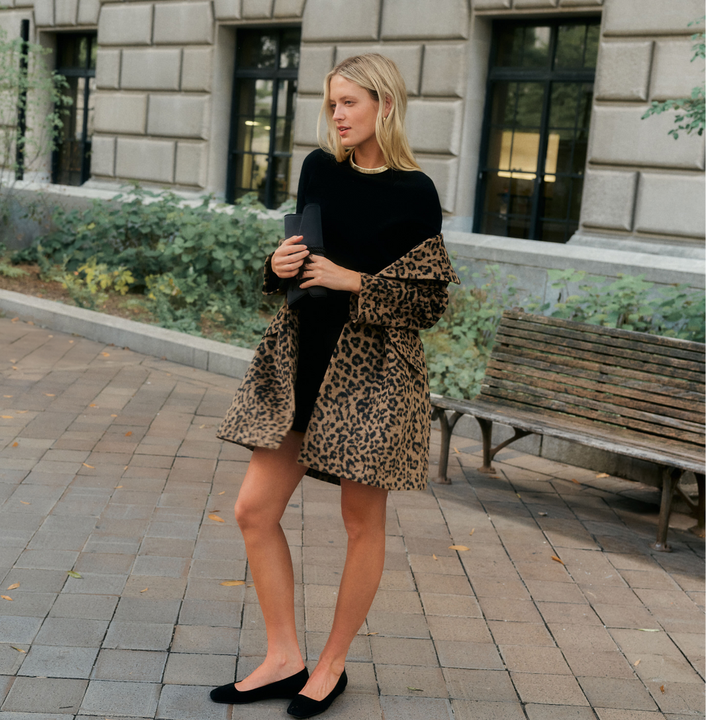 Woman in a leopard coat, black mini dress, and black ballet flats.