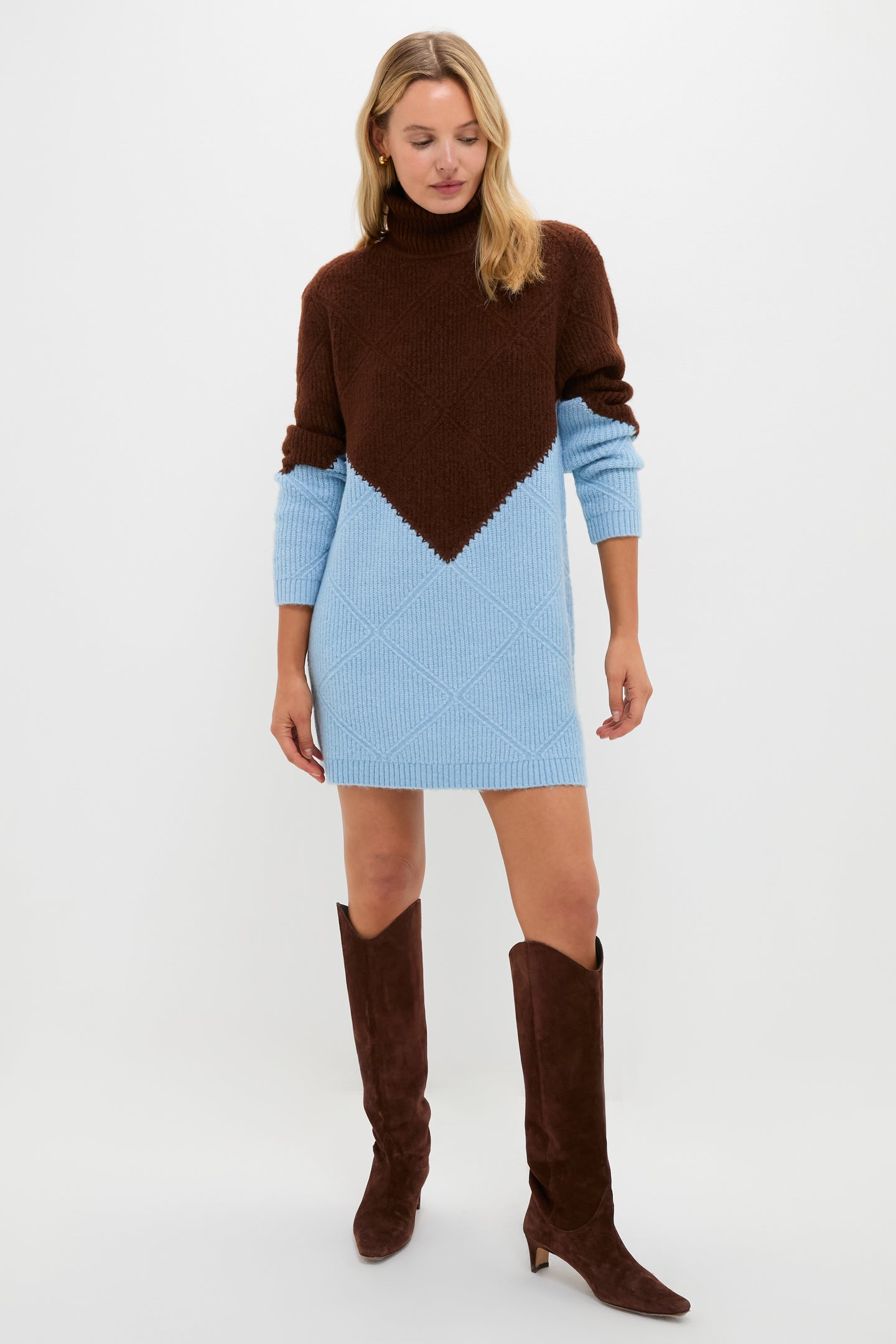 A woman wears a Hyacinth House brown and light blue turtleneck mini sweater dress with long sleeves, styled with knee-high brown suede boots.