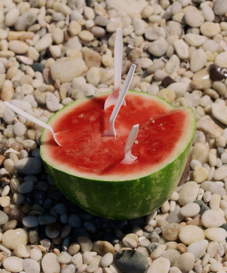 A split open watermelon on a bed of rocks.