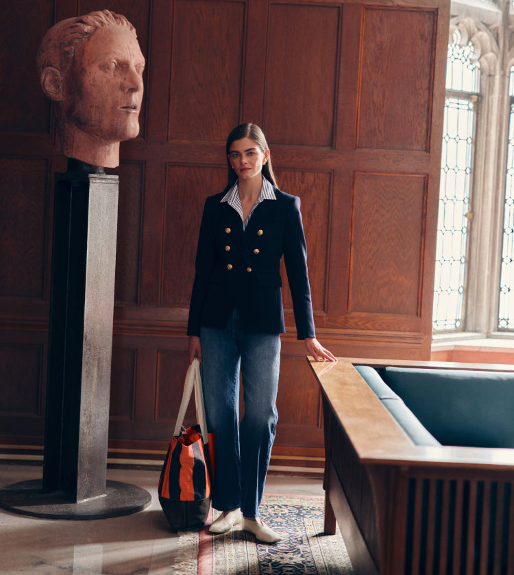 Woman standing by a statue of a head in a blazer and jeans.