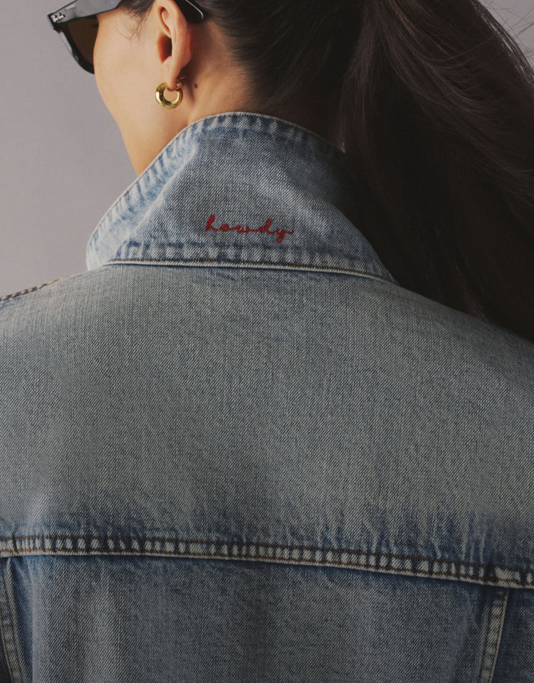 Woman wearing a denim jacket with "howdy" in red script on her collar