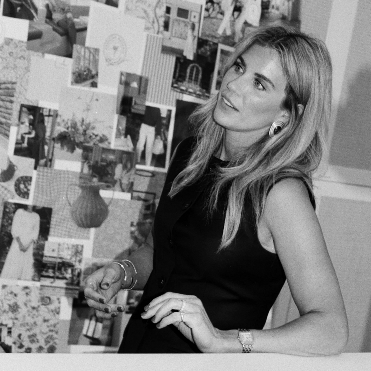 A black and white photo of Shea McGee in front of a moodboard in a black tank