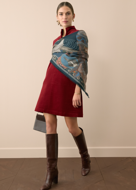 Woman in a red cord dress with a blue scarf wrapped around her body.