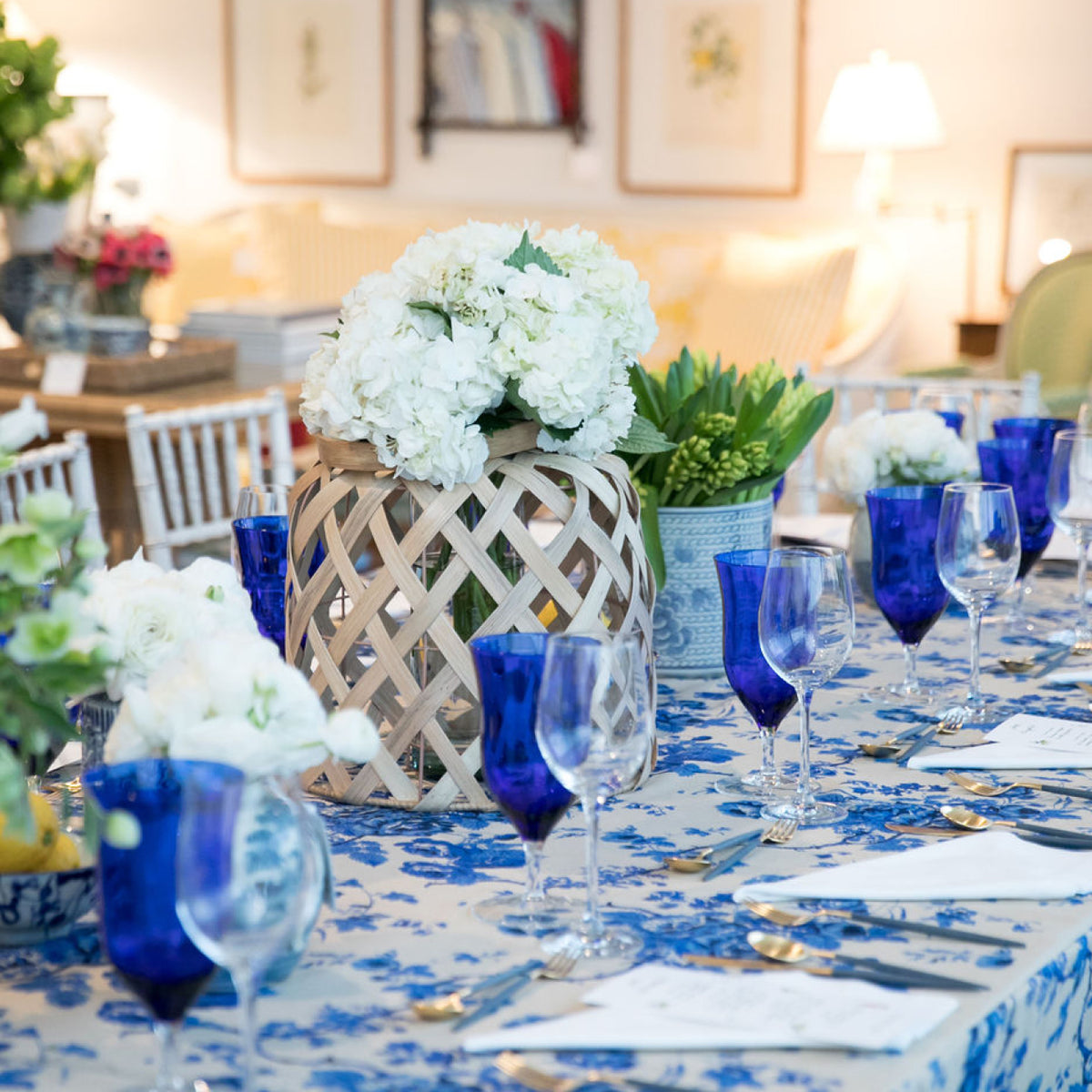 Classic dining table with blue-and-white theme, featuring gold flatware, floral centerpieces, and cobalt goblets for an effortless, high-end, and fun setting.