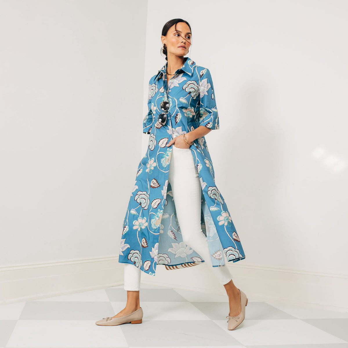Woman in a classic, effortless blue floral duster over white pants and beige flats, with gold accessories, embodying Tuckernuck's fun, high-end style.