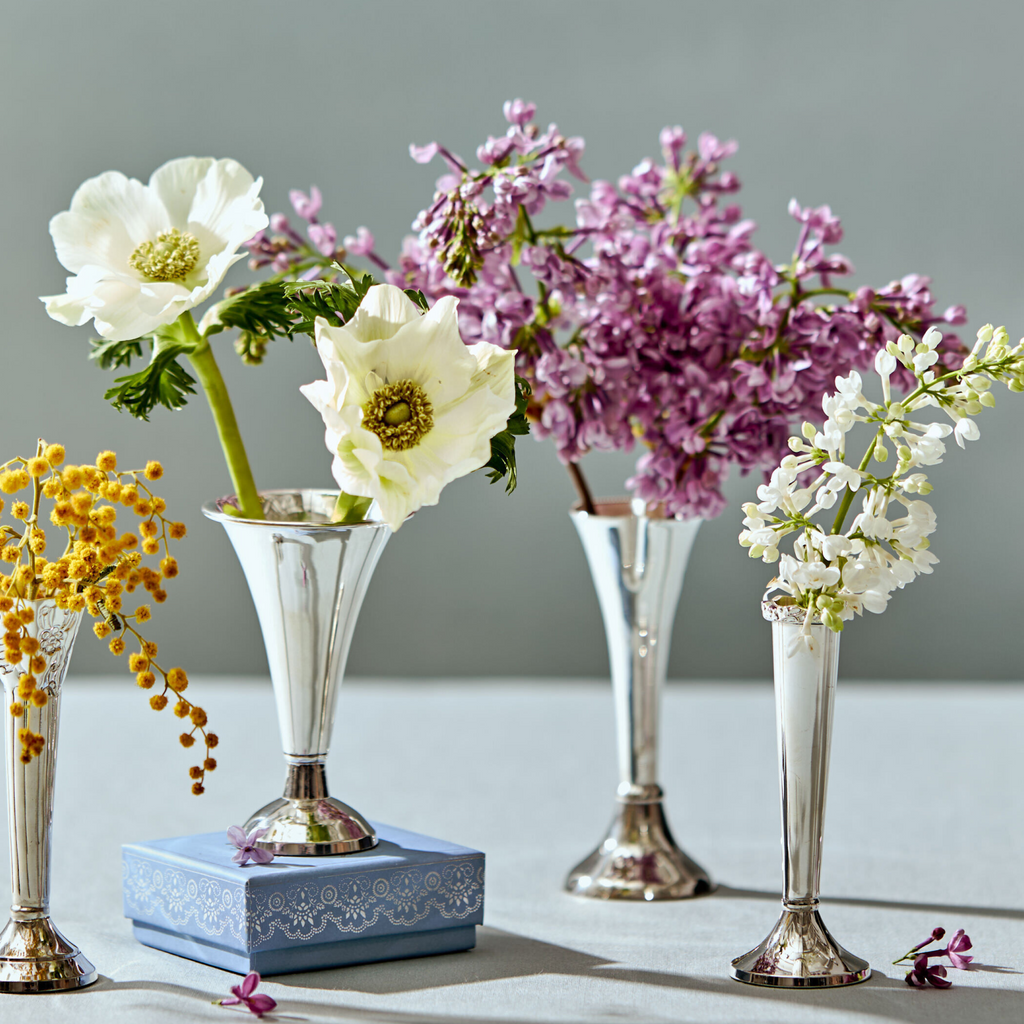 Four small silver vases filled with flowers 