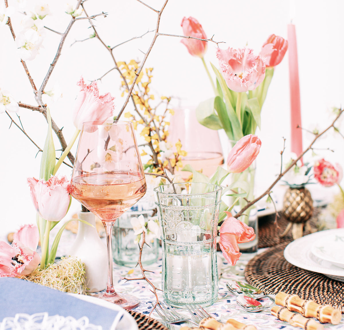 Classic spring tablescape with pink tulips, vintage glassware, floral tablecloth, and bamboo cutlery. Effortless, high-end style perfect for a fun brunch.