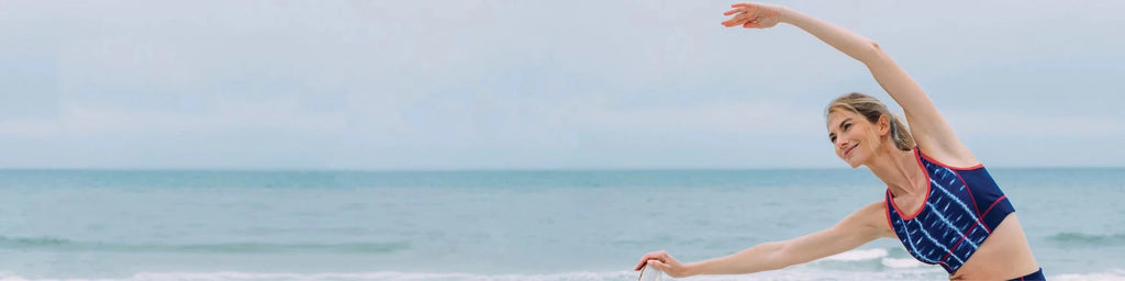 Woman at beach practicing yoga in sports outfit