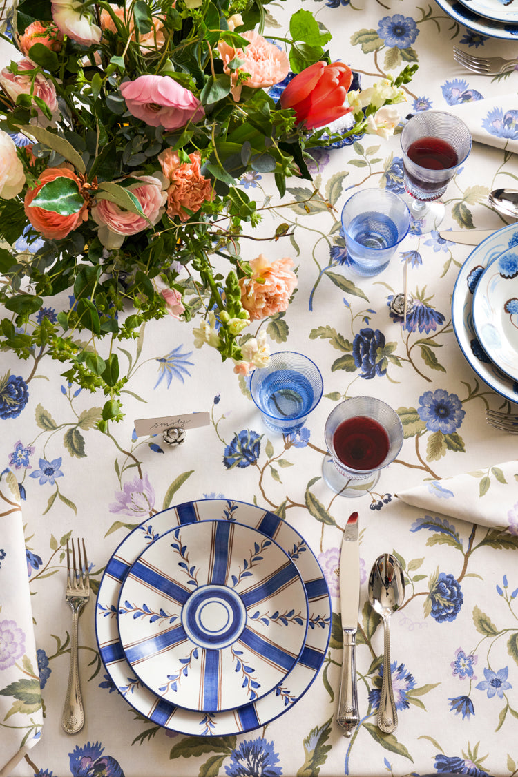 Overhead view of an elegantly set dining table featuring a classic Blue Stripe Dinner Plate, part of a high-end, effortlessly fun tablescape with floral accents.