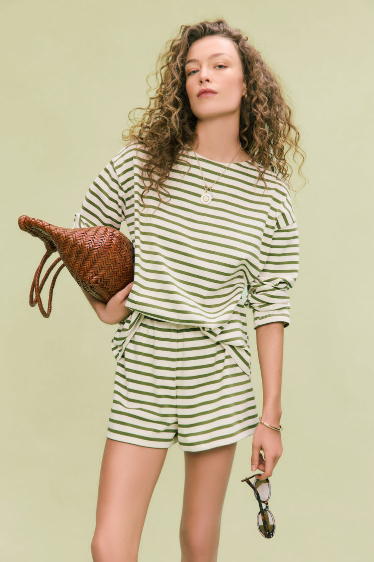 Young woman in classic Olive Stripe Knit Odie Tee and shorts, exuding effortless, high-end style with relaxed, fun vibes. Perfect for versatile, confident wear.