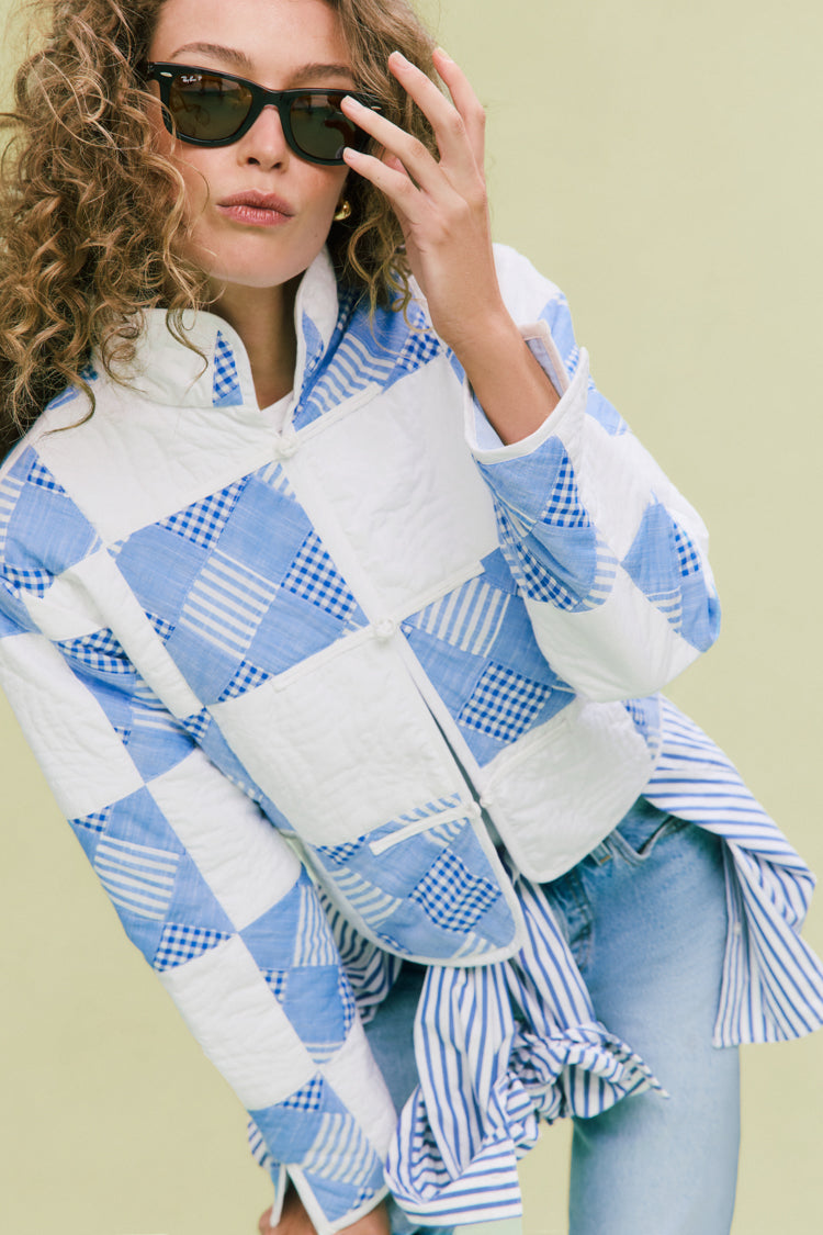 Young woman in a Blue and White Quilted Cropped Townley Jacket, adjusting sunglasses, exudes an effortless, high-end style with a relaxed, fun, and classic vibe.