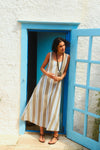Woman standing in a blue doorway in a long tank dress with blue, white, and brown stripes. 