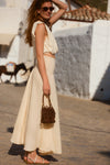 Woman posed, pulling her hair back in a cream sleeveless top and skirt. 