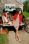 Woman sitting on the trunk of a vintage Wagoneer in a red button down and a red, white, and blue stripe dress. 