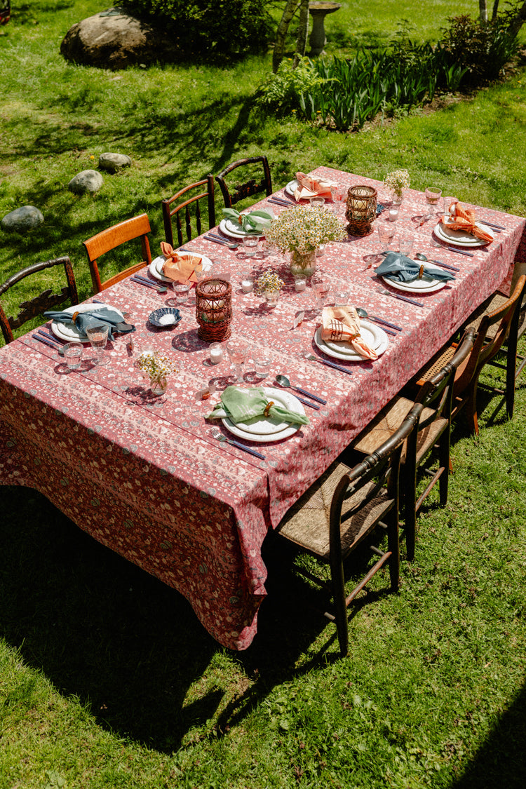 A summer table set with a red tablecloth and colorful napkins. 