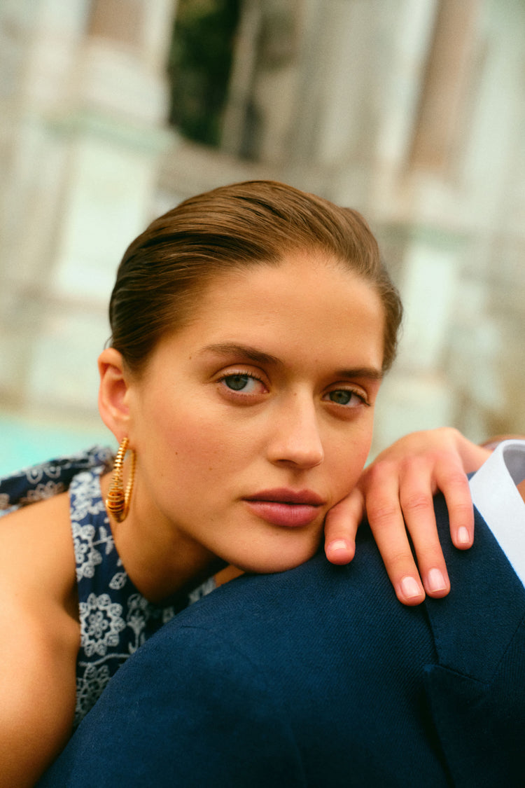 Closeup of woman leaning on a man's shoulder in a navy embroidered halter dress. 