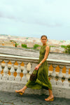 Woman walking on a balcony overlooking Rome in a green dress. 