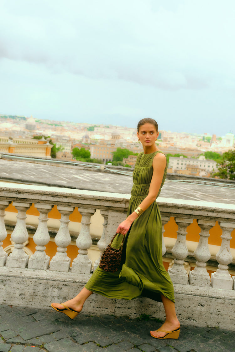 Woman walking on a balcony overlooking Rome in a green dress. 