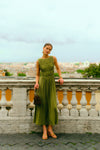 Woman standing on a balcony overlooking Rome in a green dress. 