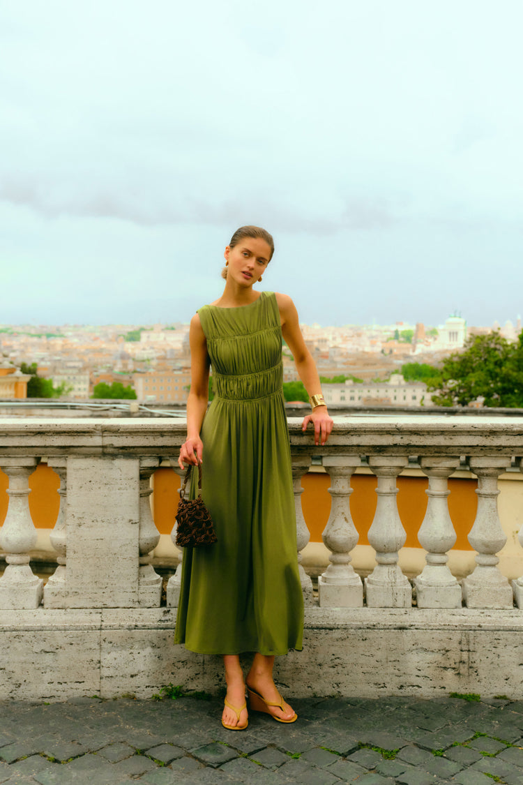 Woman standing on a balcony overlooking Rome in a green dress. 