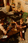 Woman sitting at a table outside of a Tuscan villa in a black and red printed caftan. 