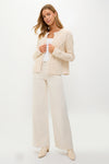 Woman wearing classic Cream Cable Knit Pearl Collins Cardigan with pearl details, paired effortlessly with matching trousers and boots, embodying a high-end, fun, and confident style.