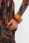 Close-up of the Oxblood and Tortoise Rita Bangle Set, featuring two chunky resin bangles on a wrist, adding classic, effortless flair to a vintage-style floral dress.