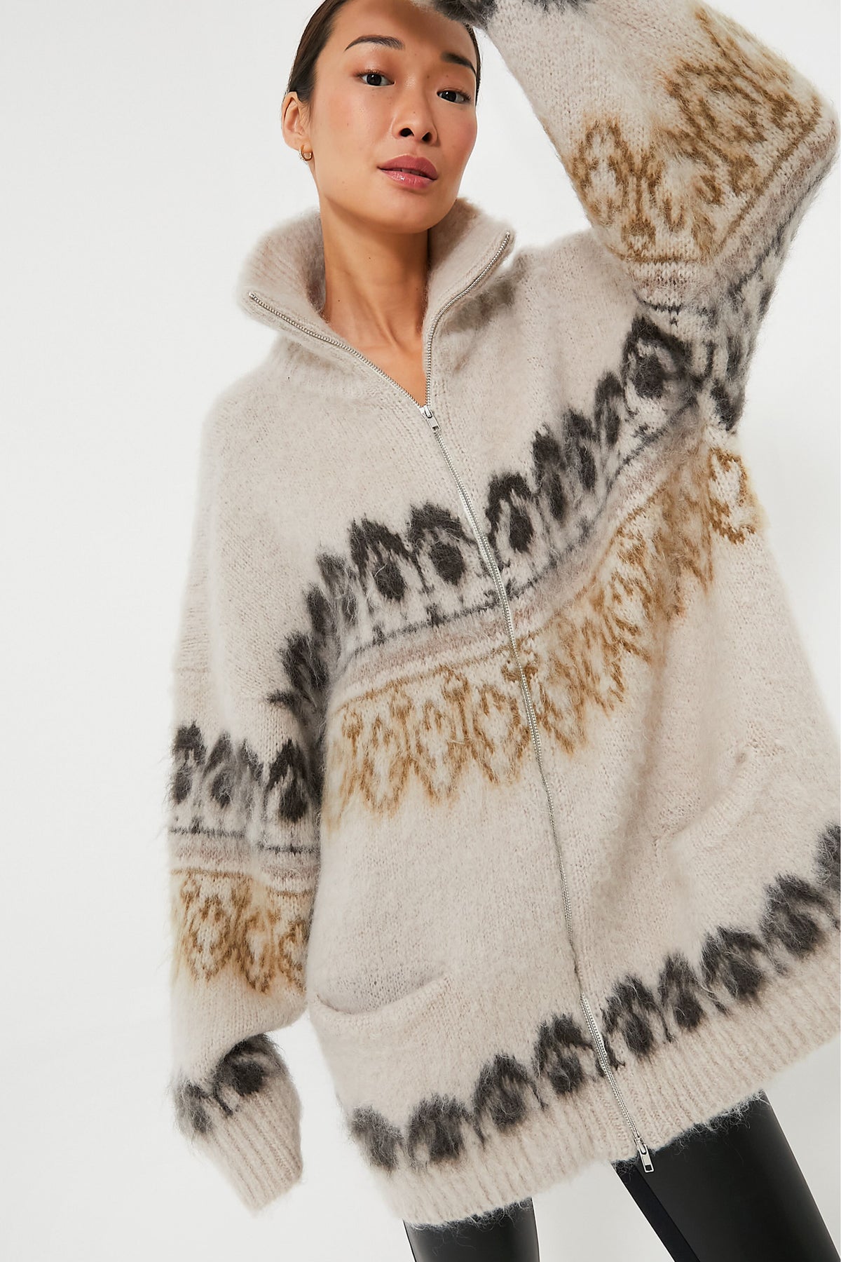 A person wearing an oversized, light beige fuzzy cardigan with black and tan patterns, styled like a khaki Deloris sweater from Isabel Marant Etoile.