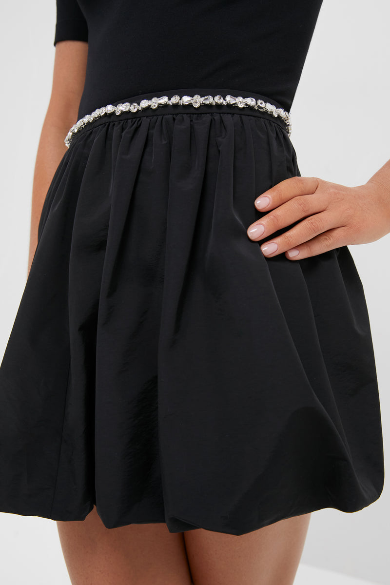 Woman wearing the Black Taffeta Embellished Camila Mini Skirt, showcasing its classic bubble silhouette and high-end, gem-studded waistband for an effortless, fun style.
