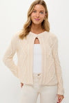 Cream Cable Knit Pearl Collins Cardigan showcases classic elegance with pearl details, worn open over a white tank, embodying an effortless, high-end, fun style.