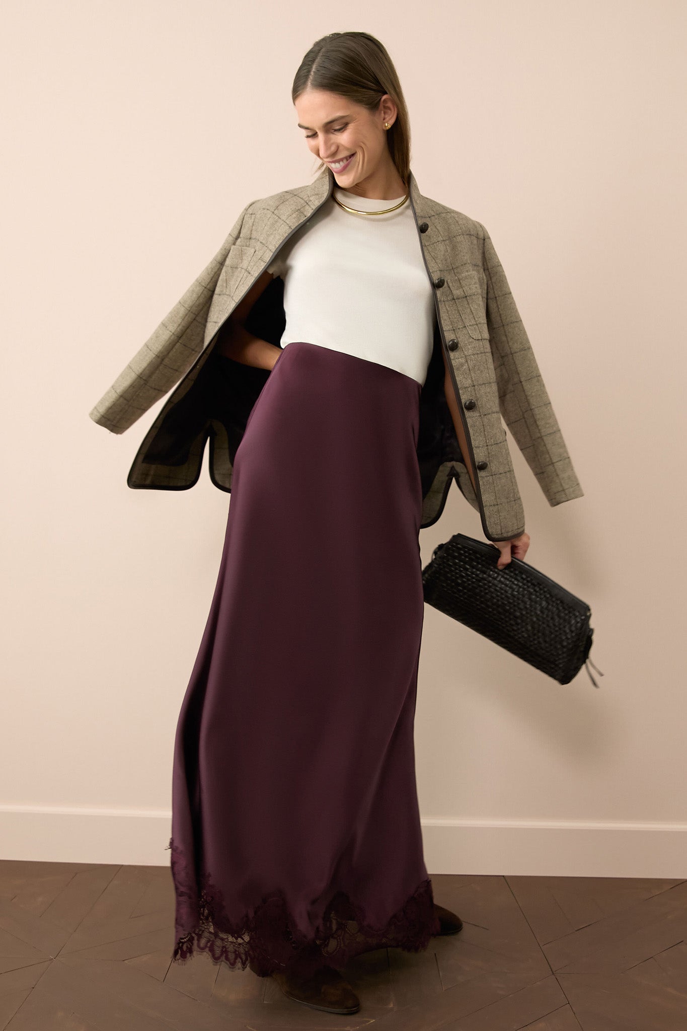 Woman models Brown Check Plaid Wool Dalton Jacket effortlessly draped over shoulders, paired with a plum slip skirt and white knit top, exuding classic, high-end style.