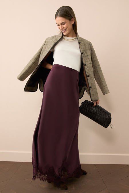 Woman models Brown Check Plaid Wool Dalton Jacket effortlessly draped over shoulders, paired with a plum slip skirt and white knit top, exuding classic, high-end style.