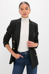 Woman wearing Black Diana Blazer with gold buttons, paired with a white turtleneck and jeans. Classic, high-end style with an effortless, fun vibe.