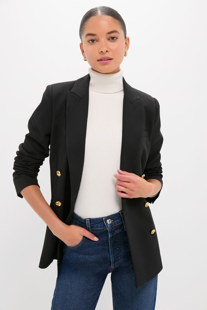 Woman wearing Black Diana Blazer with gold buttons, paired with a white turtleneck and jeans. Classic, high-end style with an effortless, fun vibe.