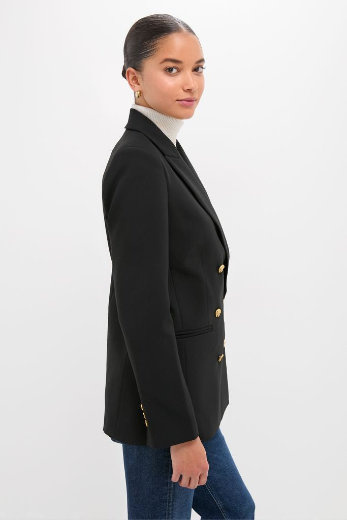 Young woman in profile wearing the classic, high-end Black Diana Blazer with gold buttons, effortlessly styled with a white turtleneck and slim jeans for a fun, timeless look.
