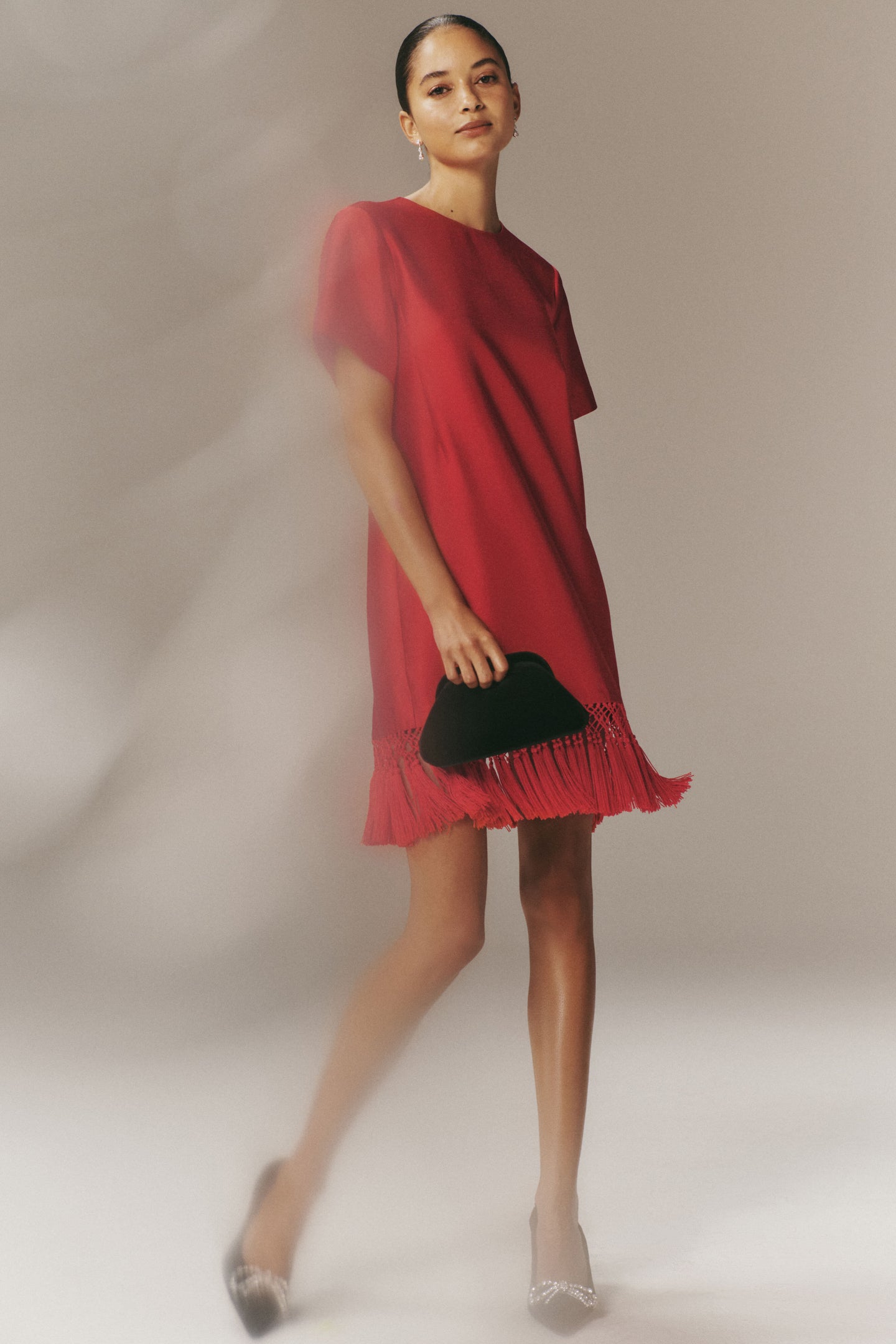 Woman in a Red Dupioni Tassel Downing Dress, holding a black clutch, styled with rhinestone-embellished heels, exuding classic elegance and effortless, high-end fun.