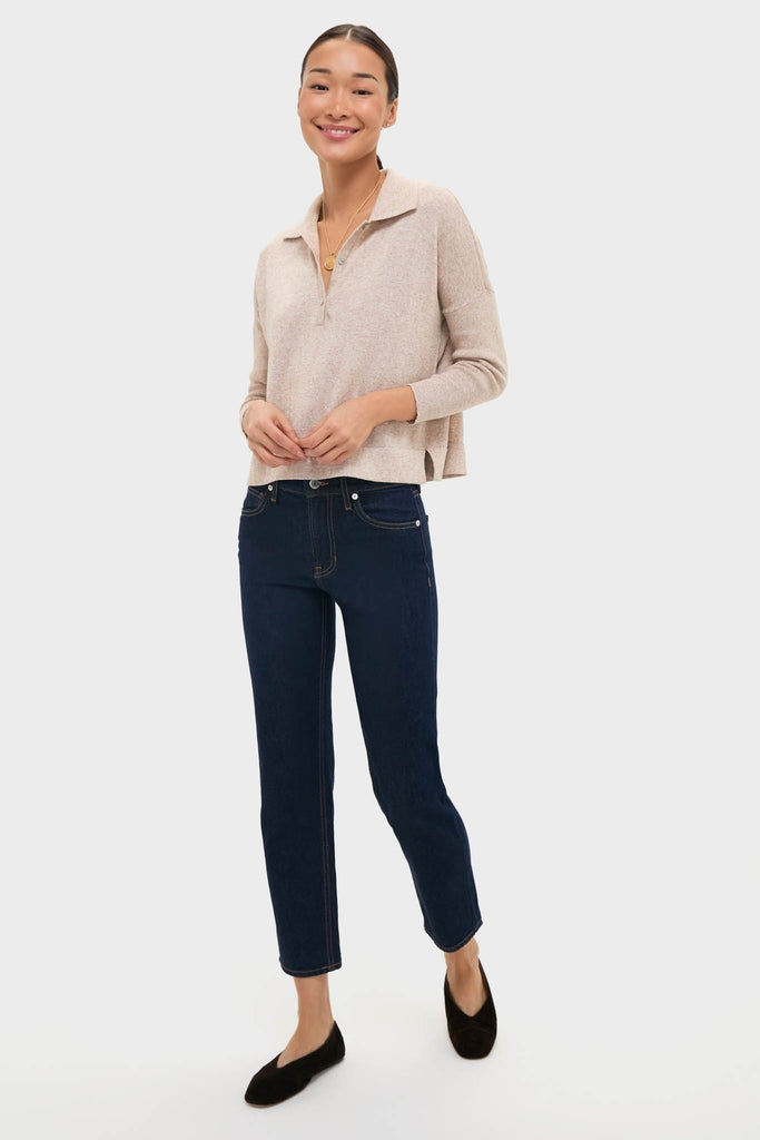 Young woman models the Tan Clayton Long Sleeve Knit Polo, showcasing its classic, effortless style with a polo collar and half-zip, paired with dark jeans and flats.