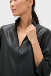 Woman wearing the Black Leather Clifton Dress with a stand collar and V-neckline, showcasing its classic and effortless style, paired with simple gold hoop earrings.